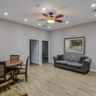 A cozy living room with a seating area, wooden flooring, and a ceiling fan.