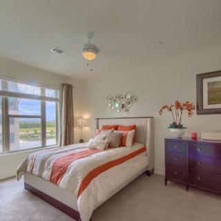 A modern bedroom with a neatly made bed and bright natural light.