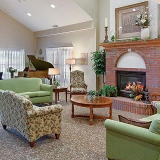 A cozy living room featuring a fireplace and comfortable seating with a piano in the corner.