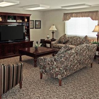 A cozy living room with floral-patterned furniture and a large television.