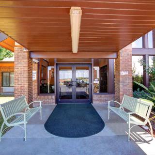 The entrance of a brick building with benches and a wooden ceiling.