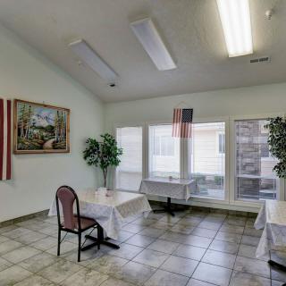 An empty room with tables and chairs, adorned with indoor plants and artwork.