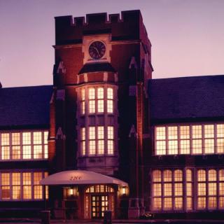 A historic building with a central clock tower illuminated in the evening.