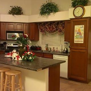 A cozy kitchen with an island, stools, and decorative plants.