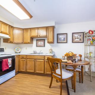 A cozy kitchen with wooden cabinets, a small dining table, and wall decor.