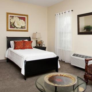 A well-decorated bedroom with a single bed, bedside lamp, and framed artwork on the wall.