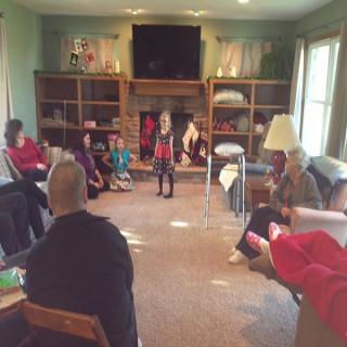 A group of people gathered in a living room, seated and conversing.