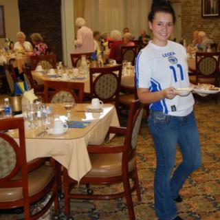 A waitress carrying plates in a busy restaurant dining room.