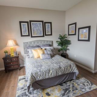 A cozy bedroom with a well-decorated bed, framed artwork on the walls, and a warm bedside lamp.
