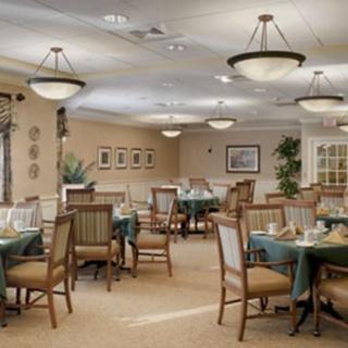 A well-lit dining area with neatly arranged tables and chairs, featuring elegant decor.