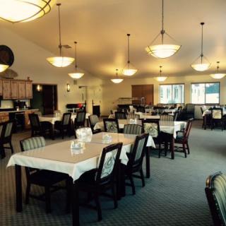 Spacious dining room with neatly arranged tables and chairs under elegant chandeliers.