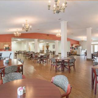 A spacious dining area with multiple tables and chairs, adorned with chandeliers.