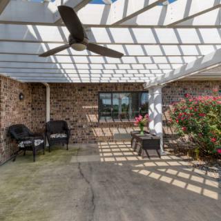 A cozy patio with a pergola, featuring outdoor seating and vibrant plants.