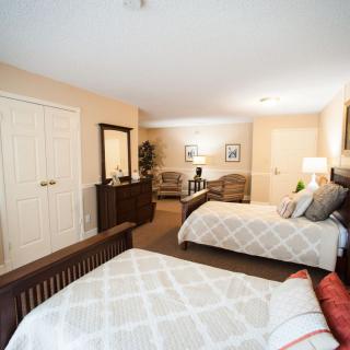 A spacious bedroom with two beds, elegant furniture, and warm lighting.