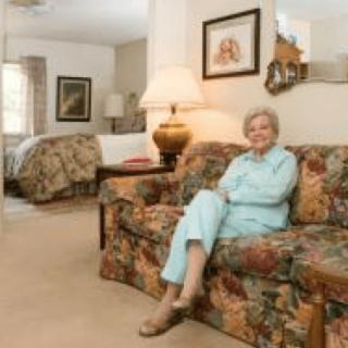 A woman sits comfortably on a floral-patterned couch in a cozy living room.