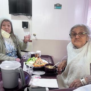 Two elderly women enjoying a meal together in a cozy setting.