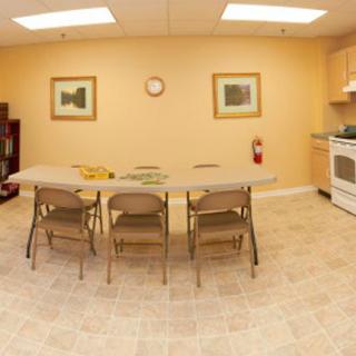 A simple kitchen setup with a table, chairs, and appliances.