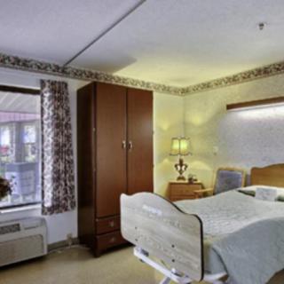 A hospital room with a bed, wardrobe, and bedside lamp.