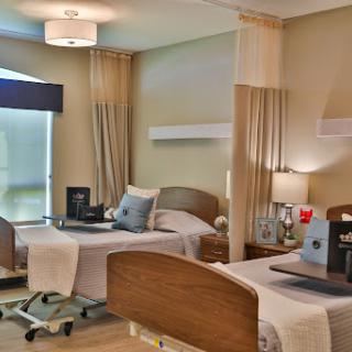 A modern hospital patient room designed for comfort and functionality, featuring two beds and a warm color palette.