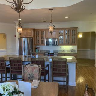 A modern kitchen with a large island counter and dining area, featuring stainless steel appliances and elegant pendant lighting.