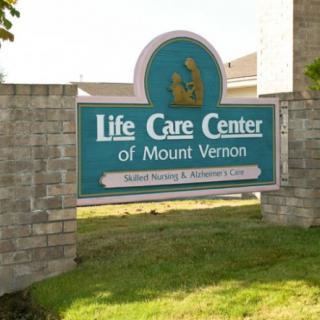 A sign for the Life Care Center of Mount Vernon is displayed on a brick wall.