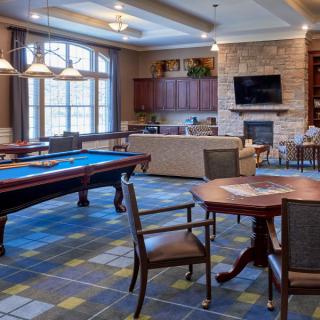 A cozy recreational space featuring a pool table, seating area, and a fireplace with a TV above.