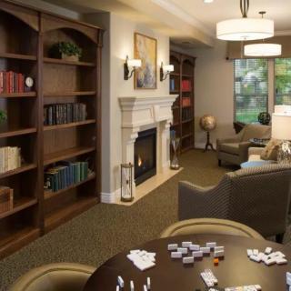 A cozy library room with bookshelves, a fireplace, and comfortable seating.