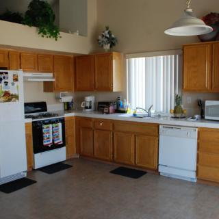 A spacious kitchen with wooden cabinets, equipped with modern appliances including a stove, refrigerator, microwave, and dishwasher.