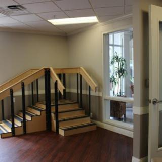 A view of an office interior featuring a staircase and a window with greenery.