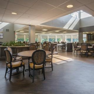 A spacious dining area with natural light streaming through skylights, featuring tables, chairs, and indoor plants.