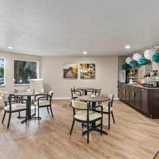 A cozy dining area with several tables and chairs, featuring tasteful decorations and a hardwood floor.