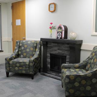 A cozy waiting area featuring patterned chairs and a decorative fireplace.