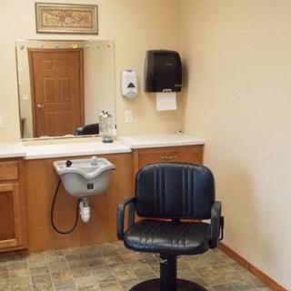 An interior view of a salon with a barber chair, sink, and mirror.