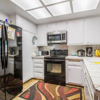 Modern kitchen with sleek appliances and a vibrant rug.