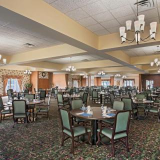 A spacious dining room with neatly arranged tables and chairs, featuring elegant chandeliers.