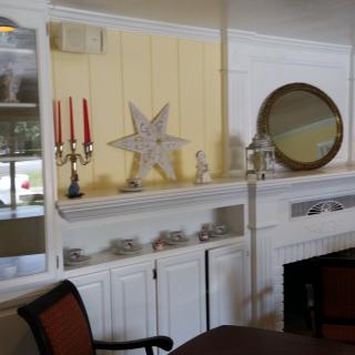 A cozy interior featuring a decorated fireplace with candles, a star ornament, and a round mirror.