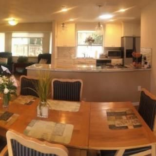A cozy dining area connected to a modern kitchen with wooden furniture and bright lighting.
