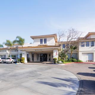 Exterior view of a hotel entrance with surrounding parking area.