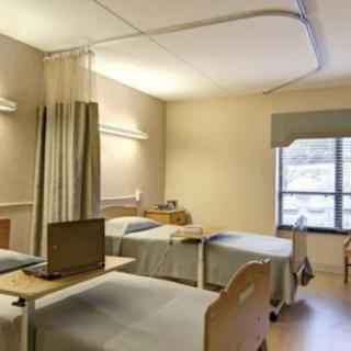 A hospital room with multiple beds and a window.