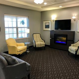 A cozy living room with comfortable chairs, a fireplace, and a mounted television.