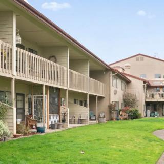 A residential apartment complex with balconies and a well-maintained lawn.