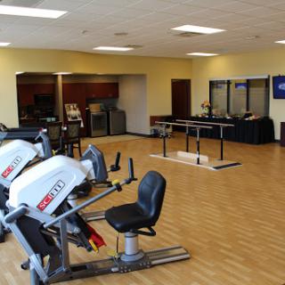 A spacious gym featuring cardio machines and a well-lit workout area.