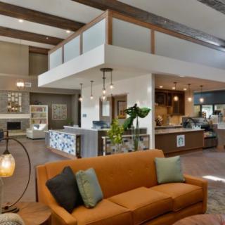 A modern open-concept living space featuring a cozy orange sofa, a spacious kitchen area, and contemporary decor.
