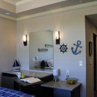 A bedroom with nautical-themed decor, featuring an anchor and ship wheel wall art, a mirror, and a sailboat model.