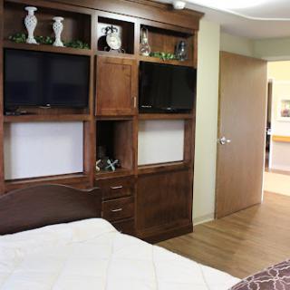 A cozy bedroom featuring wooden furniture, including cabinets with televisions and decorative items.