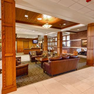 A warmly lit hotel lobby with comfortable seating and elegant wood paneling.