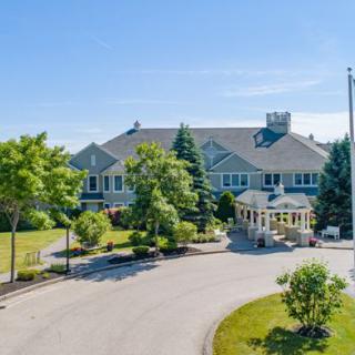 A large mansion surrounded by lush greenery and a circular driveway under a clear blue sky.