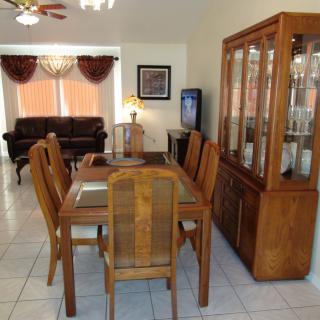A dining area with wooden furniture and a cabinet, connecting to a living room.