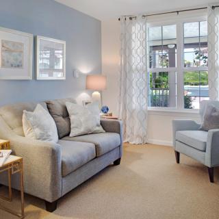 A cozy living room with a sofa, armchair, and natural light.