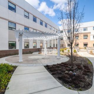 A modern building with a landscaped courtyard and a pathway leading to an outdoor structure.